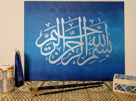 a blue painting with white calligraphy on it next to some pens and other art supplies