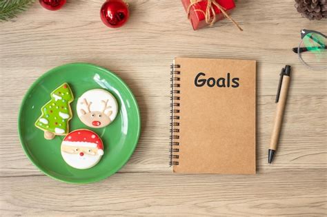 Premium Photo | Goal with notebook black christmas cookies and pen on wood table top view and ...