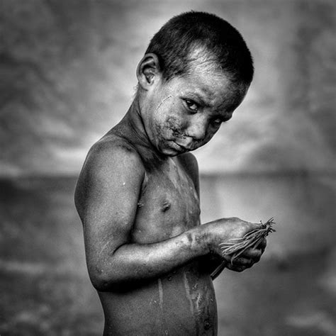 black and white photograph of a young boy with mud on his face, holding flowers