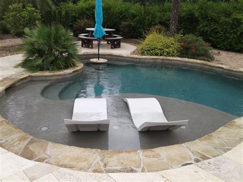 Freeform pool with tanning ledge, ledge loungers, rock waterfall ...