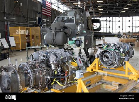 The engines of an AH-64 Apache helicopter await to be hoisted and connected to the helicopter ...