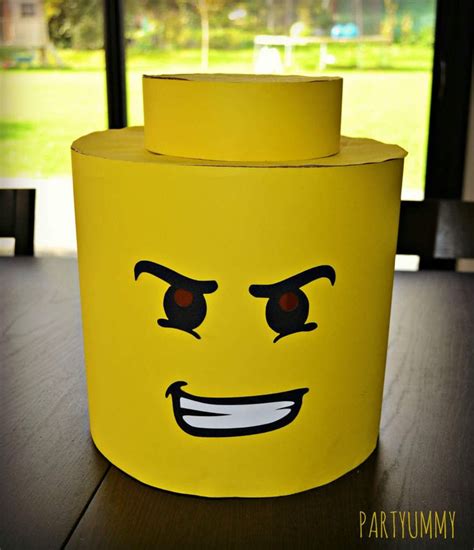 a yellow plastic container with eyes and mouth on a wooden table in front of a window