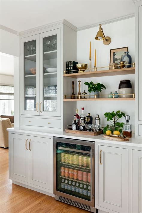 a kitchen with white cabinets and shelves filled with drinks on top of ...