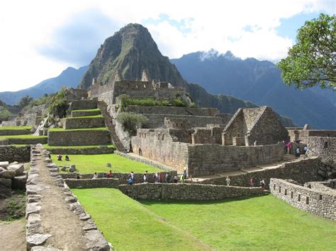 people are standing in front of the ruins at machu pico, with mountains in the background