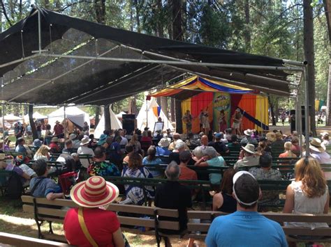 a crowd of people sitting on top of benches under a tent in the park ...