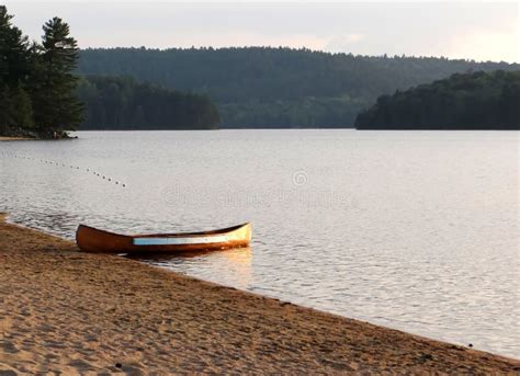 Canoe on Quiet Sandy Beach of Forest Mountains Lake in the Evening. La ...