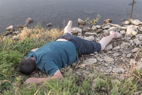 The Body Of A Man Dead From Drowning Lies On The Riverbank Stock Photo - Download Image Now - iStock