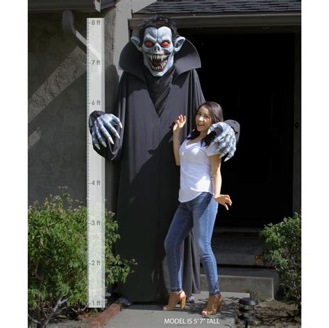 a woman standing next to a giant statue of a creepy monster with her hands in the air