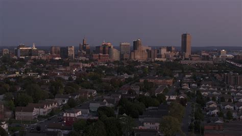 5.7K stock footage aerial video of the skyline seen while flying past homes at twilight ...