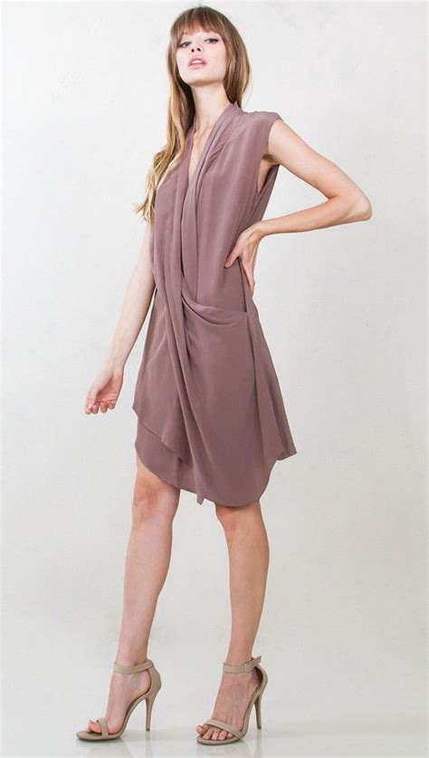 The Taupe of the World Dress features a taupe cap sleeve draped dress with a wrap front and ...