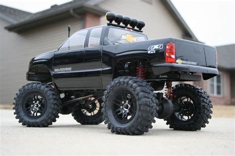 a black truck with big tires parked in front of a house