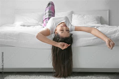 Young woman lying upside down in bed at home Stock Photo | Adobe Stock