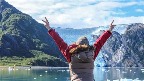 a woman standing on top of a boat in the water with her arms outstretched up