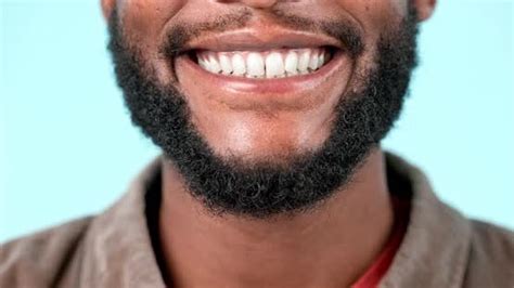 Teeth, closeup and black man with a smile in studio, blue background or ...