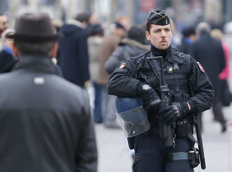 French police officer of the Gendarmerie Nationale in riot control gear standing guard with a ...