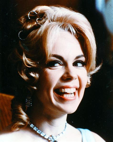 a woman with blonde hair wearing a necklace and smiling