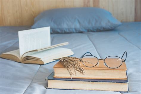 Libro abierto con flores secas y pila de libros en la cama en el ...