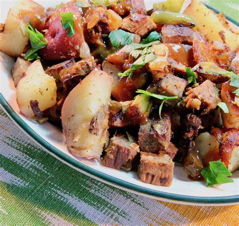 a white plate topped with potatoes and meat next to a green napkin on top of a table