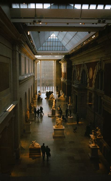 people are walking through an indoor museum with statues on the walls ...