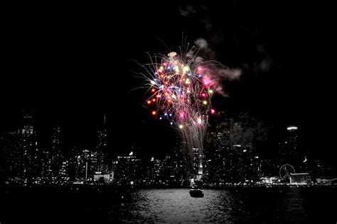 fireworks are lit up in the night sky over water and city skylines at night