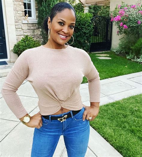 a woman standing in front of a house with her hands on her hips and smiling