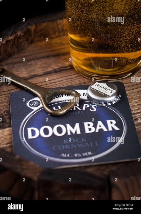 LONDON, UK - AUGUST 10, 2018: Doom bar beer coaster with bottle top and opener and glass of beer ...