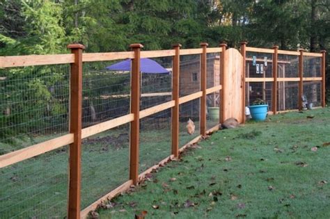 a wooden fence with wire around it and chickens in the yard behind it ...