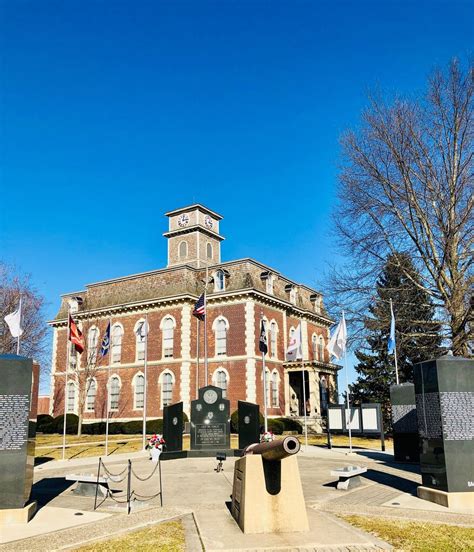 an old brick building with flags flying in the wind and sculptures on the ground around it