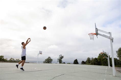 Male teenage basketball player throwing ball toward basketball hoop stock photo