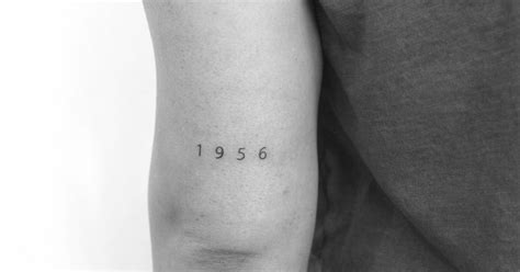 "1956" lettering tattoo done on the tricep.