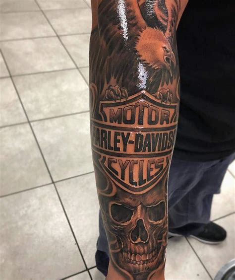 a man's arm with an eagle and harley davidson logo tattooed on the forearm