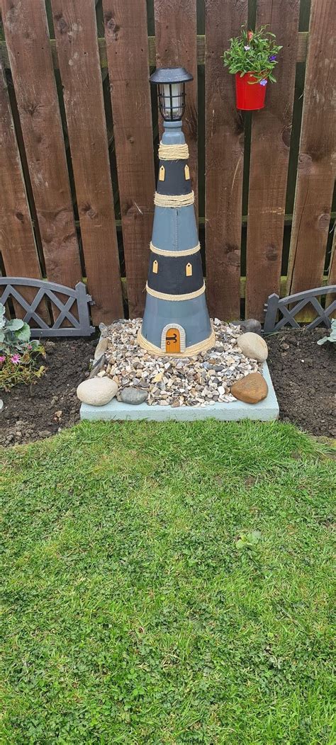 there is a small blue and white lighthouse in the grass next to a wooden fence