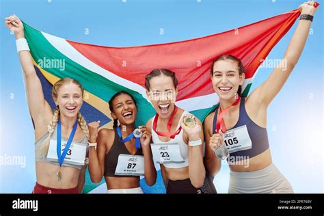 Portrait diverse group of female olympic athletes holding winners medals and African flag. Happy ...