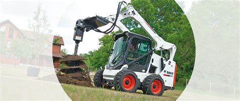 Bobcat skid-steer loader planting tree with auger attachment.