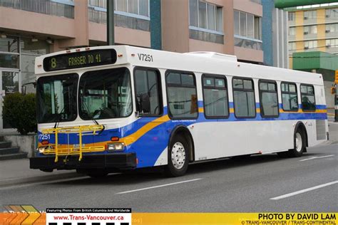 a blue and white bus driving down the street in front of a tall building with windows