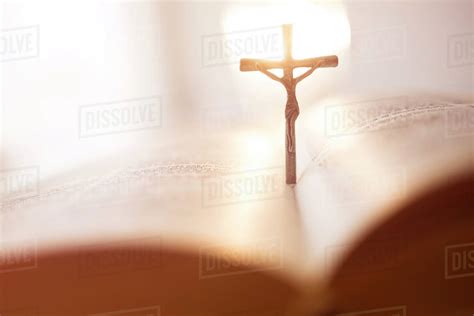 Backlit cross in open Bible - Stock Photo - Dissolve