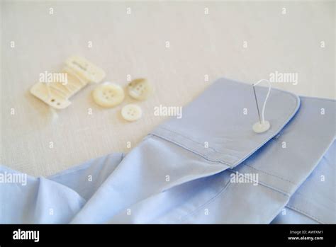 Sewing button on shirt Stock Photo - Alamy