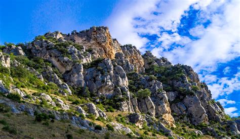 Rock Formation with Green Shrubs Under Blue Sky · Free Stock Photo