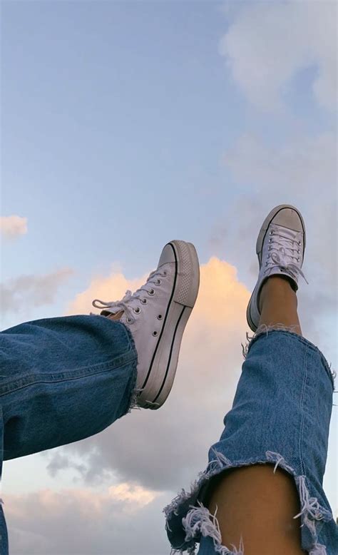 two people standing next to each other with their feet up in the air and clouds behind them