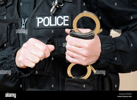 Police officer holding handcuffs Stock Photo - Alamy