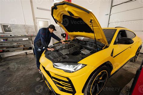 Mechanic open hood of yellow sport car suv. 14703345 Stock Photo at Vecteezy