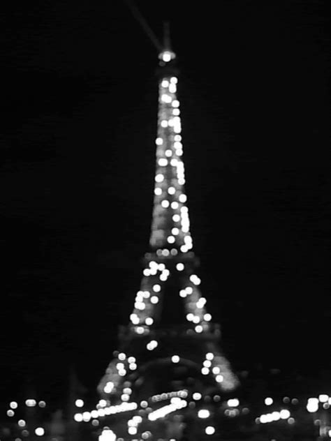 the eiffel tower lit up at night in black and white with blurry lights