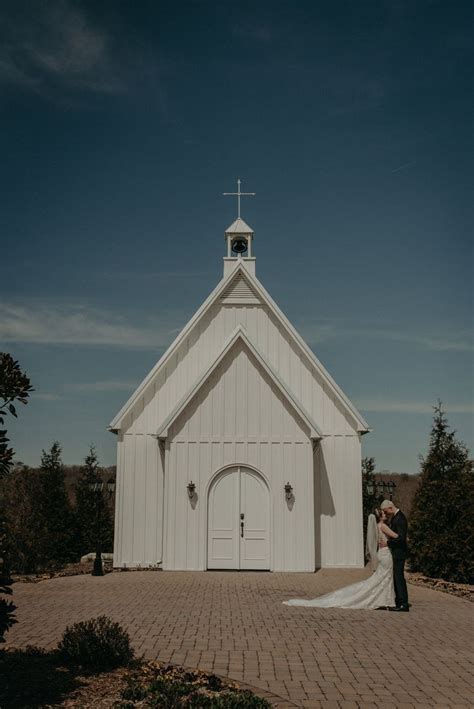 Couple shares a first look together in front of a white chapel at the Howe Farms wedding ven ...