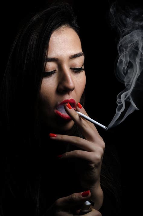 Portrait of the beautiful elegant girl smoking cigarette on black background. Photograph by Ivan ...