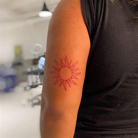 Red sun tattoo located on the tricep, fine line style.