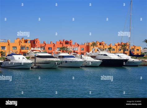 PORTIMAO, PORTUGAL. A row of luxury yachts berthed in front of colourful apartments in the ...