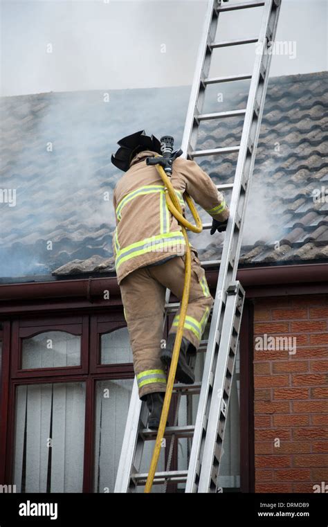 Firefighter carrying hose up ladder roof house fire Stock Photo - Alamy