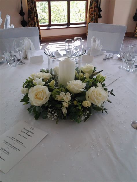 Wedding reception table decoration made using fresh flowers and fol ...