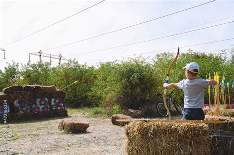 Little boy, kid with bow and arrow aiming at archery target in park ...