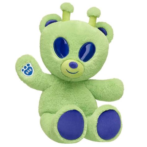 a green teddy bear with blue eyes on it's head and paws up in the air